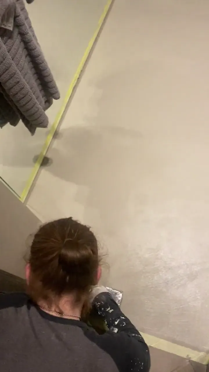 Hand application of microcement to a bathroom wall