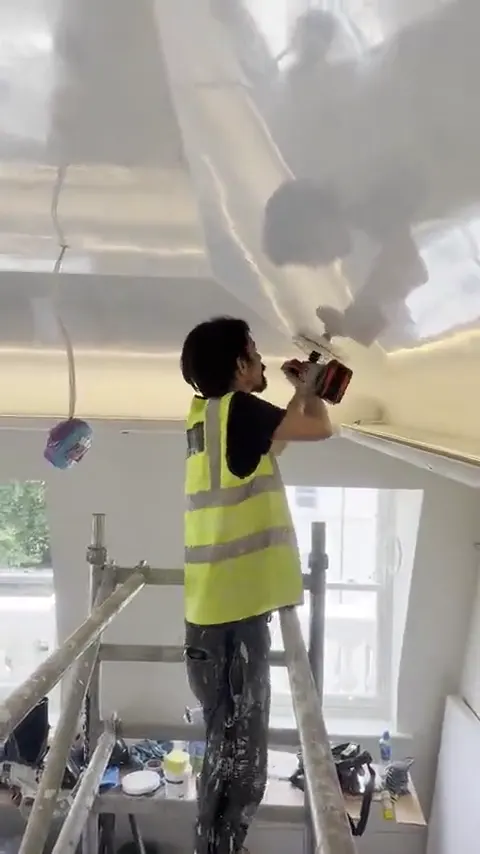 Plasterer mechanically polishing a detailed polished plaster ceiling