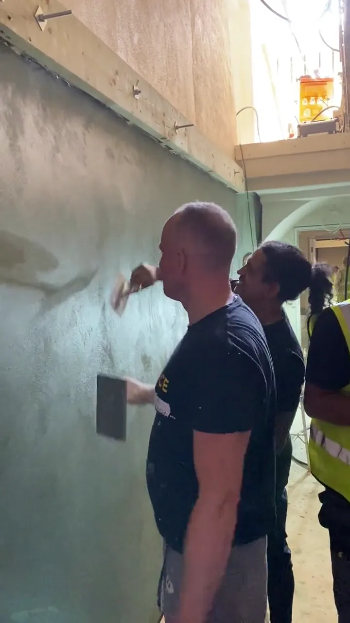 Two plasterers hand-applying tadelakt to a curved wall